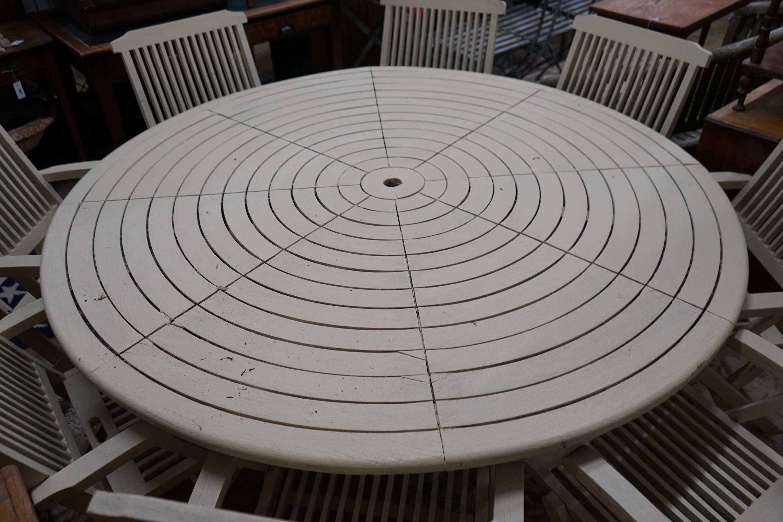 A circular painted teak garden table, diameter 180cm, height 72cm and eight matching folding garden elbow chairs